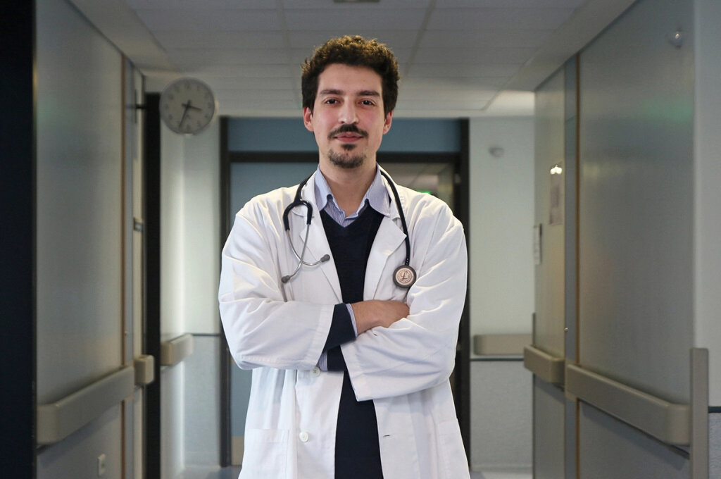 Fotografia do Prof. Doutor João Sérgio Neves ao centro da imagem com os braços cruzados. Ao fundo aparece um corredor hospitalar.